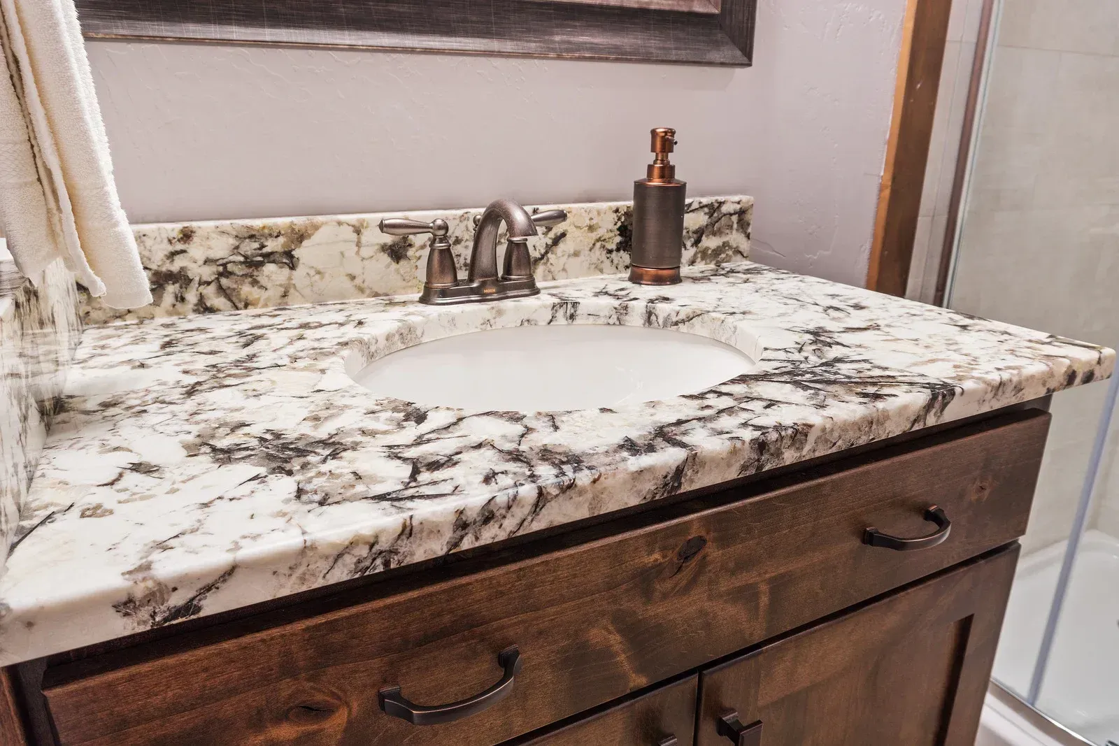 A bathroom vanity with a marble counter top and a sink.