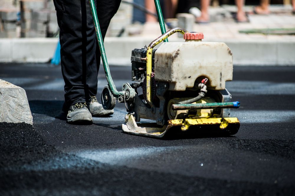 A Person is Using a Machine to Compact Asphalt on a Road — Dino's Bobcat–Bitumen & Excavator Hire in Cushnie, QLD