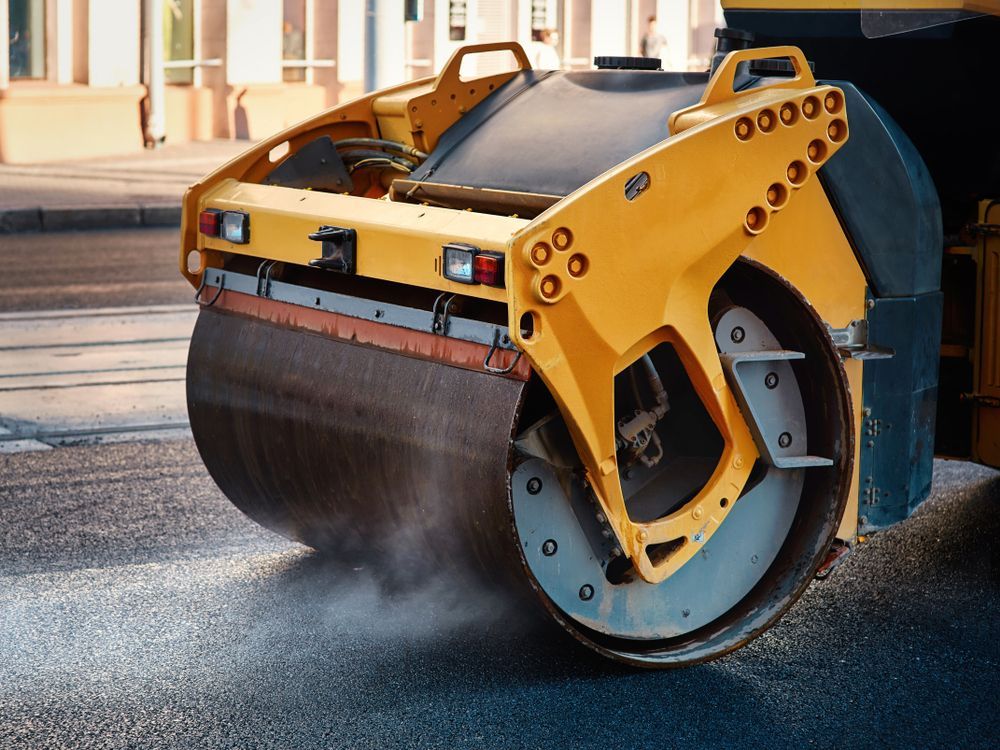 A Yellow Road Roller is Rolling Asphalt on a City Street — Dino's Bobcat–Bitumen & Excavator Hire in Cushnie, QLD