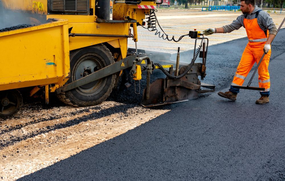 A Man is Working on a Road With a Machine — Dino's Bobcat–Bitumen & Excavator Hire in Proston, QLD