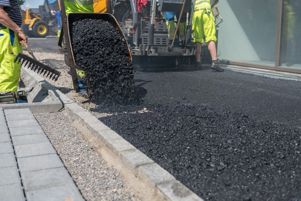 A Group of Construction Workers Are Laying Asphalt on a Sidewalk — Dino's Bobcat–Bitumen & Excavator Hire in Cushnie, QLD