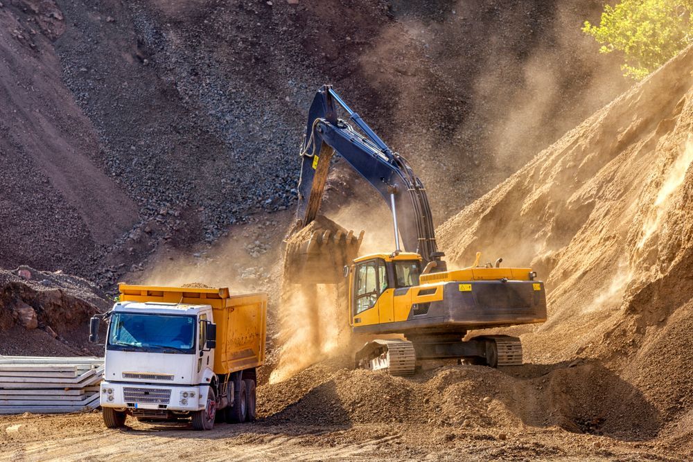 An Excavator is Loading Dirt Into a Dump Truck — Dino's Bobcat–Bitumen & Excavator Hire in Kingaroy, QLD