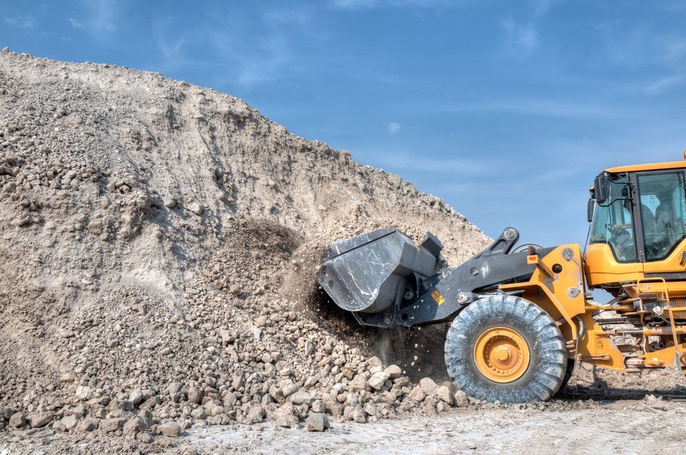 A Bulldozer is Loading Dirt Into a Bucket on a Construction Site — Dino's Bobcat–Bitumen & Excavator Hire in Wondai, QLD