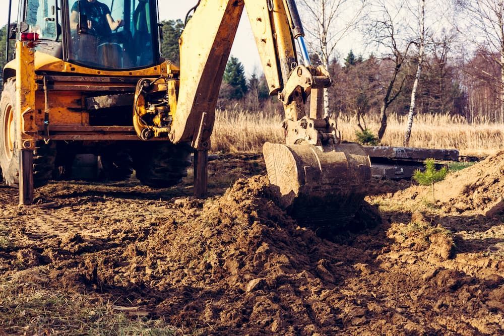 A Yellow Excavator is Digging a Hole in the Dirt — Dino's Bobcat–Bitumen & Excavator Hire in Cushnie, QLD