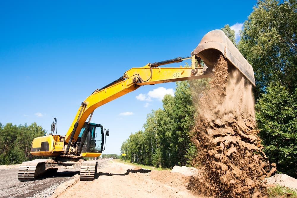 An Excavator is Loading Dirt Into a Bucket — Dino's Bobcat–Bitumen & Excavator Hire in South Burnett, QLD