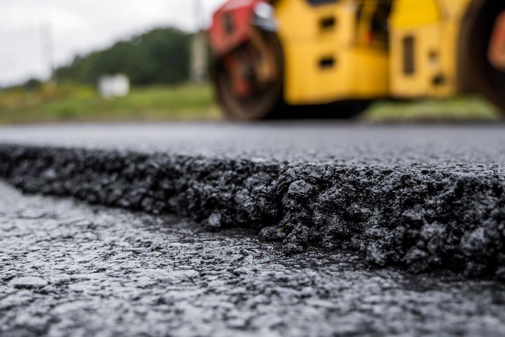 A Yellow Roller is Rolling Asphalt on a Road — Dino's Bobcat–Bitumen & Excavator Hire in Proston, QLD