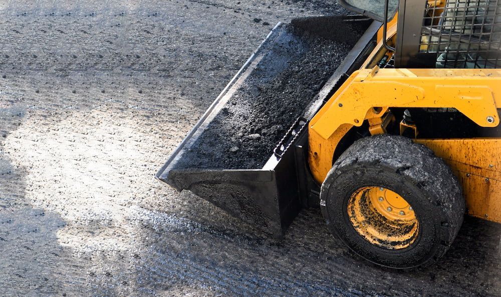 A Yellow Bulldozer is Moving Dirt on a Road — Dino's Bobcat–Bitumen & Excavator Hire in Kingaroy, QLD