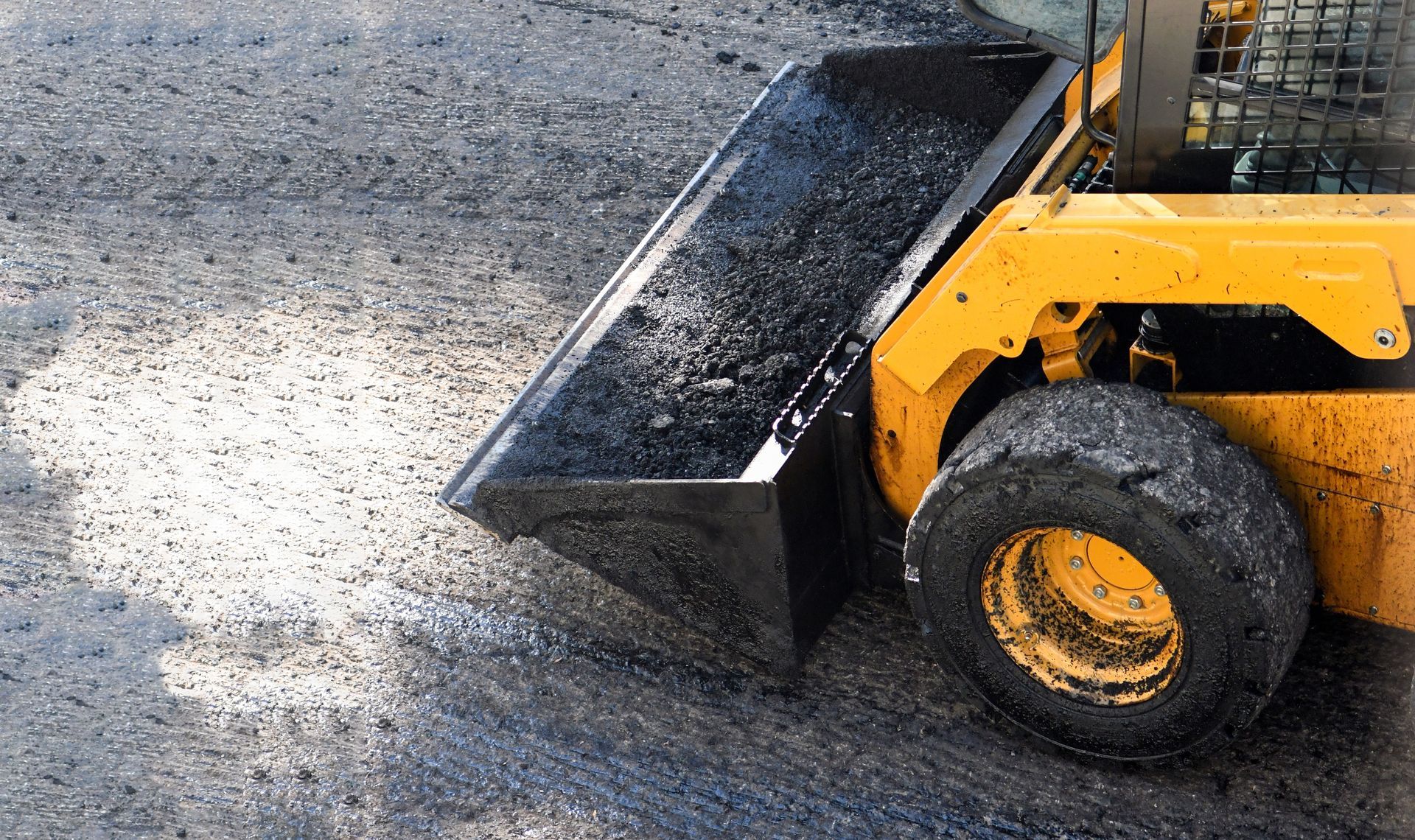 A Yellow Bulldozer is Scooping Dirt From the Ground — Dino's Bobcat–Bitumen & Excavator Hire in South Burnett, QLD