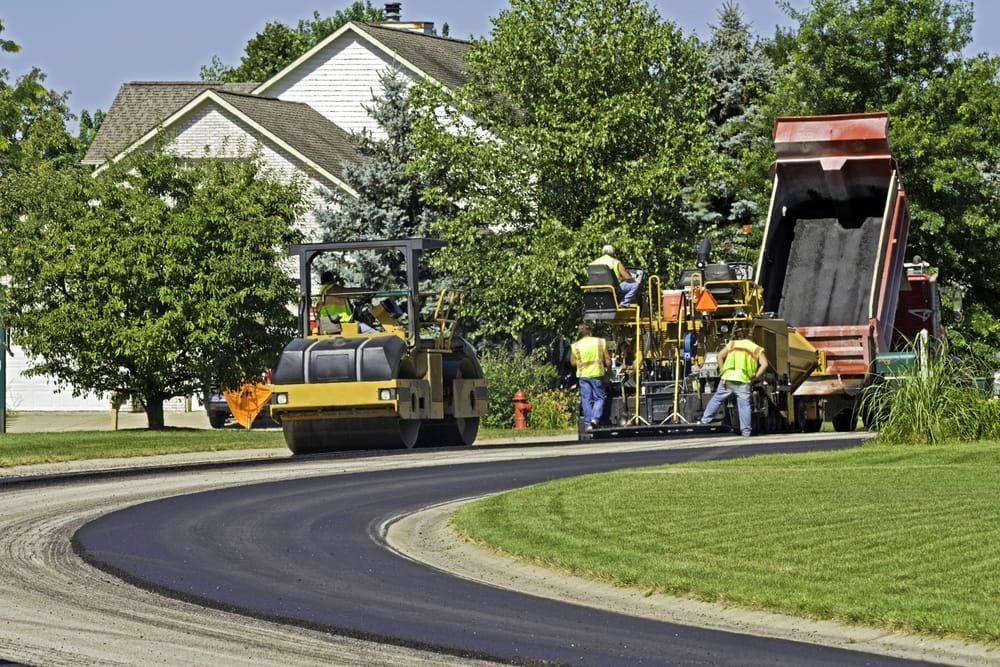 A Road is Being Paved in a Residential Neighborhood — Dino's Bobcat–Bitumen & Excavator Hire in Cushnie, QLD