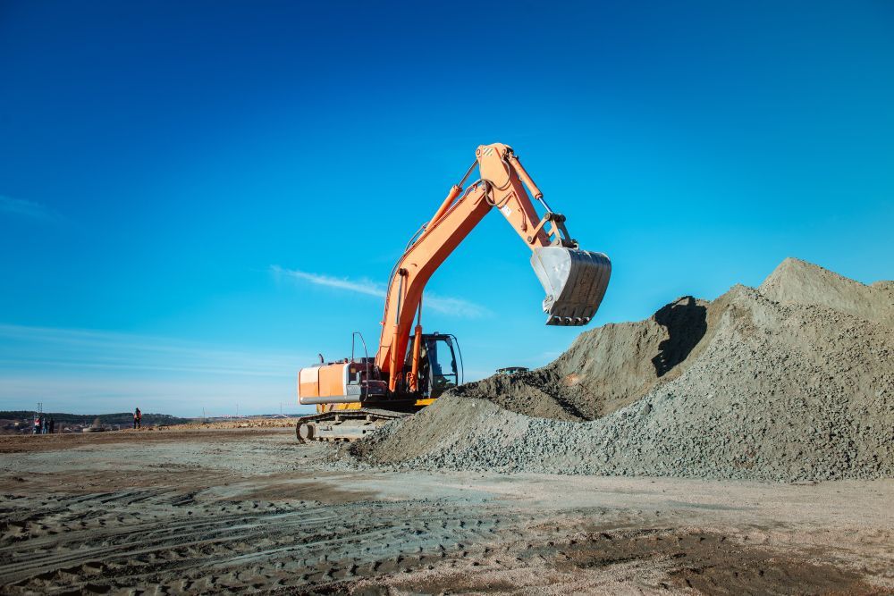 An Orange Excavator is Digging a Pile of Dirt on a Construction Site — Dino's Bobcat–Bitumen & Excavator Hire in Proston, QLD