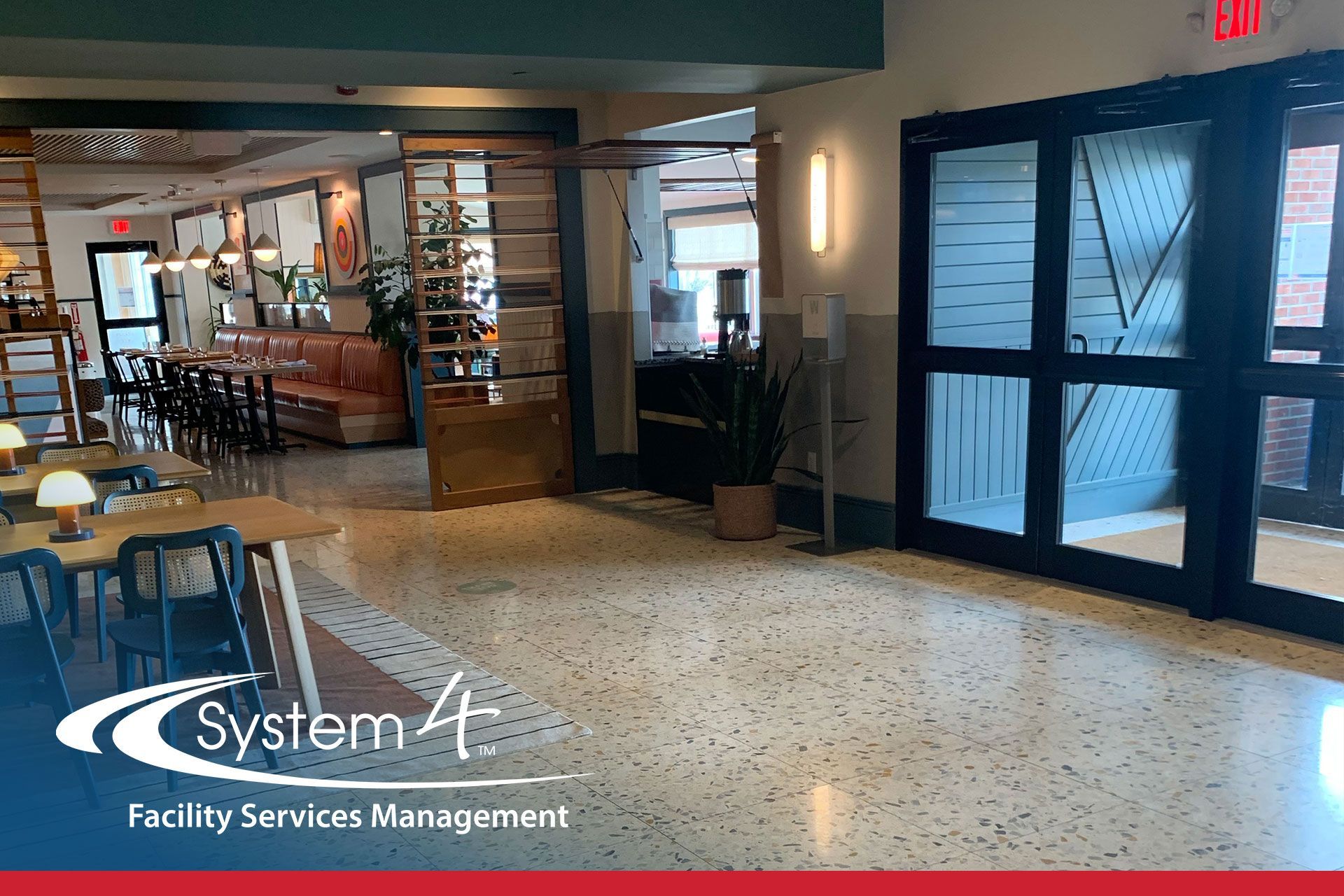 Hotel lobby with glass entrance doors, seating area, and “System4 Facility Services Management” sign