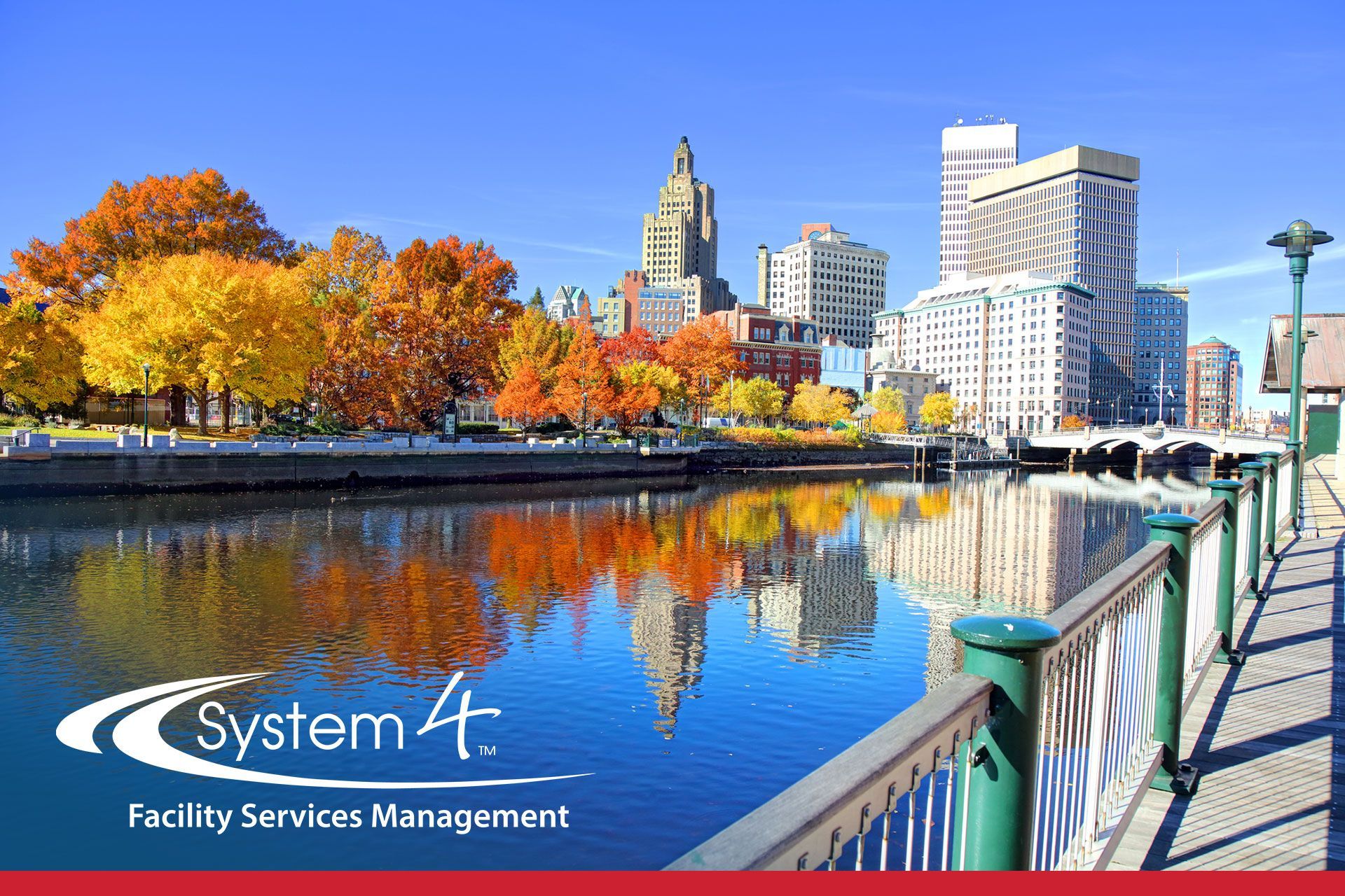 Autumn city skyline reflected in a calm river beside a riverside walkway and railing