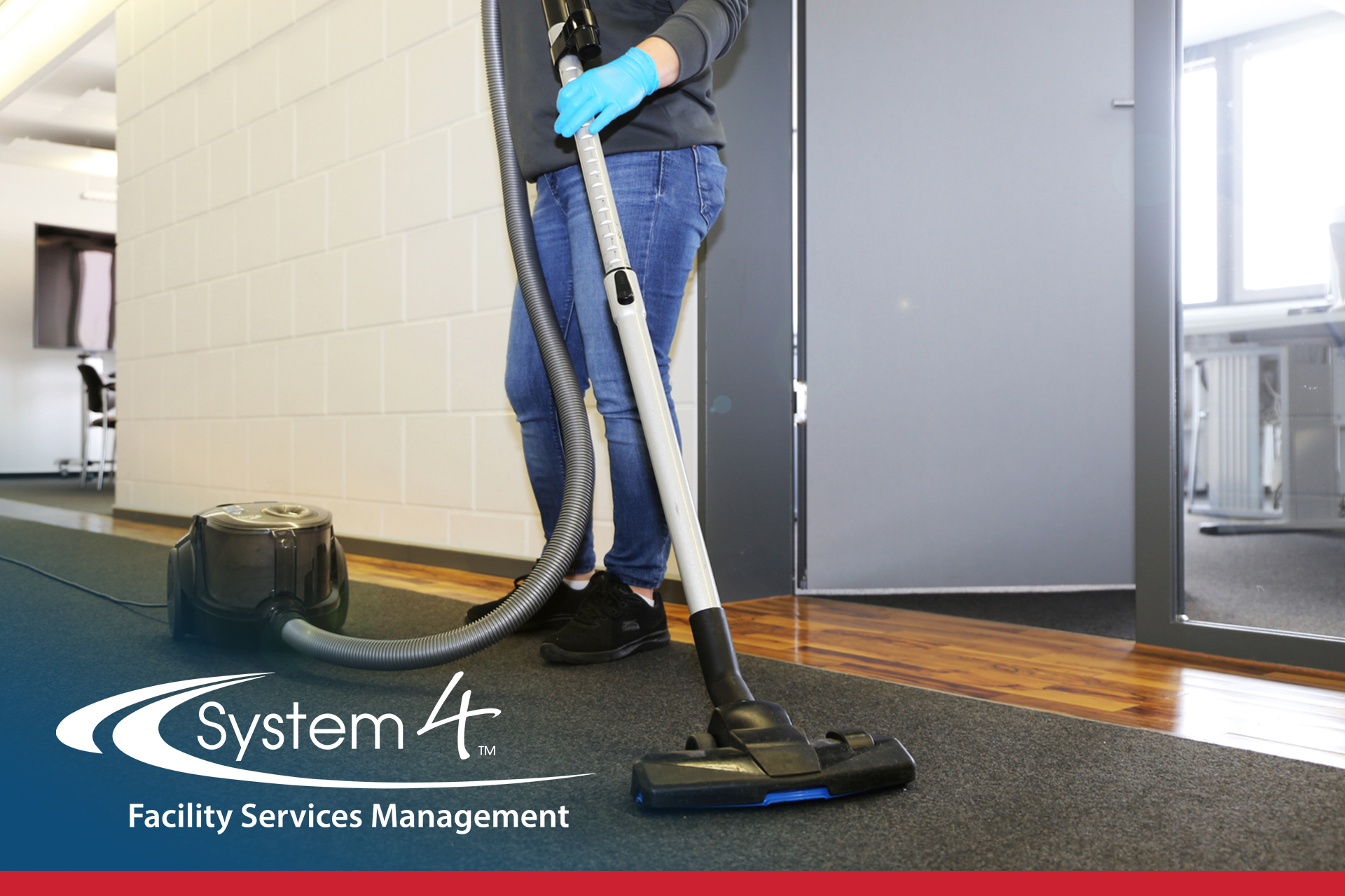 Janitor vacuuming a hallway with a canister vacuum and floor attachment
