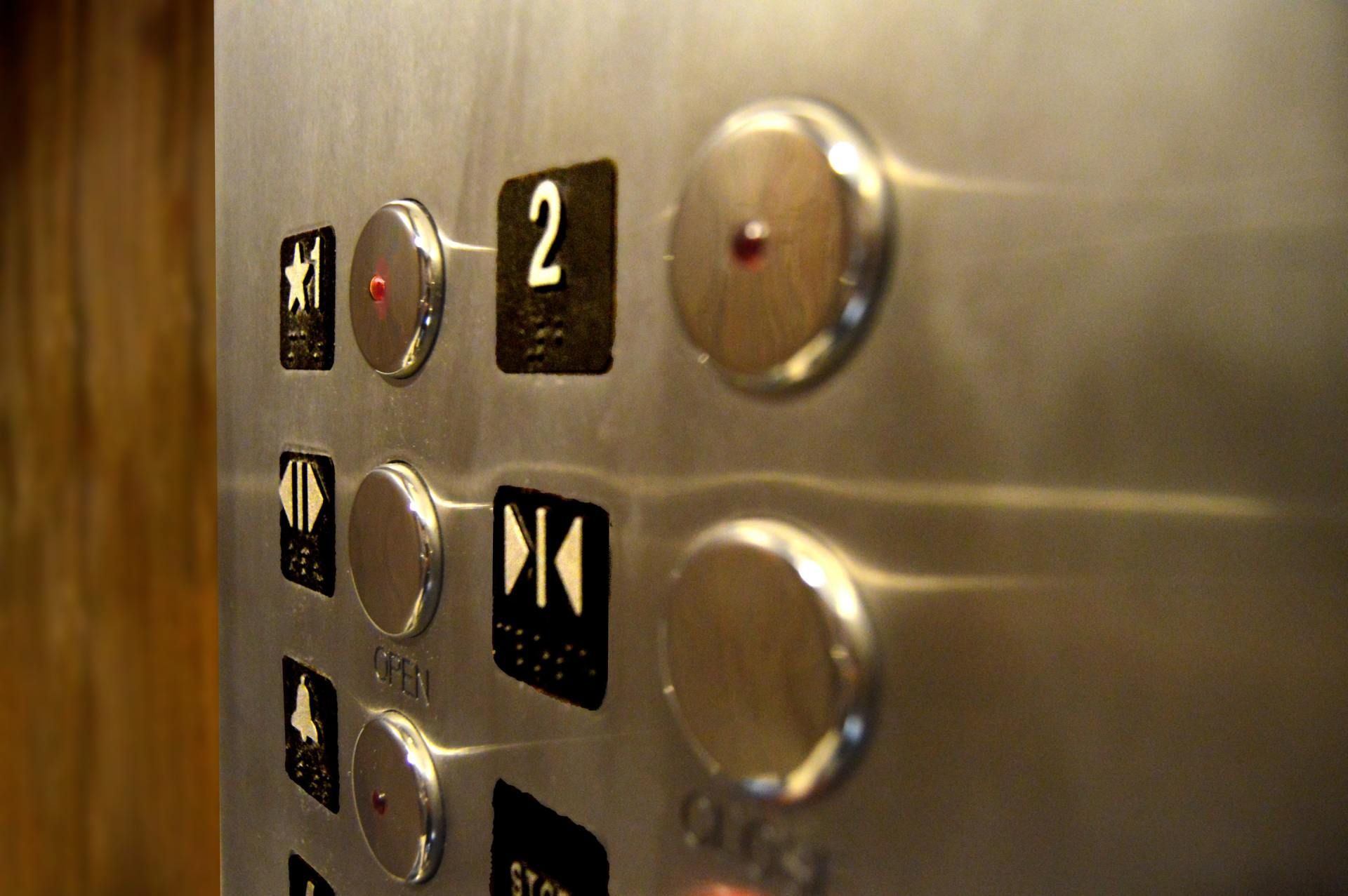 Close-up of an elevator panel with round silver buttons and a lit floor 2 button.