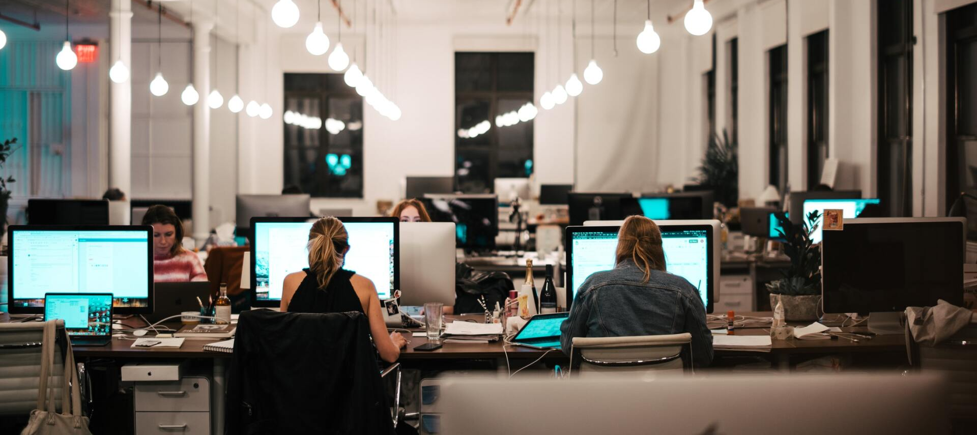 Open-plan office with several people working at computers in a bright, modern workspace