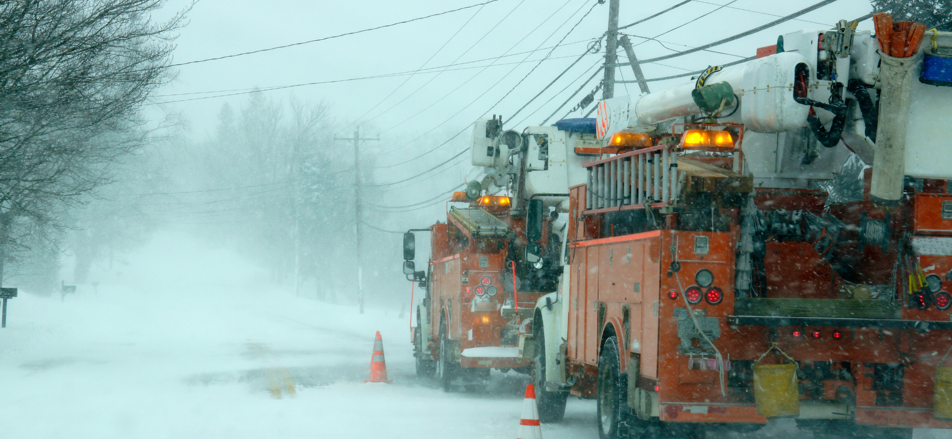 Snowplows clearing a snow-covered road in a heavy winter storm