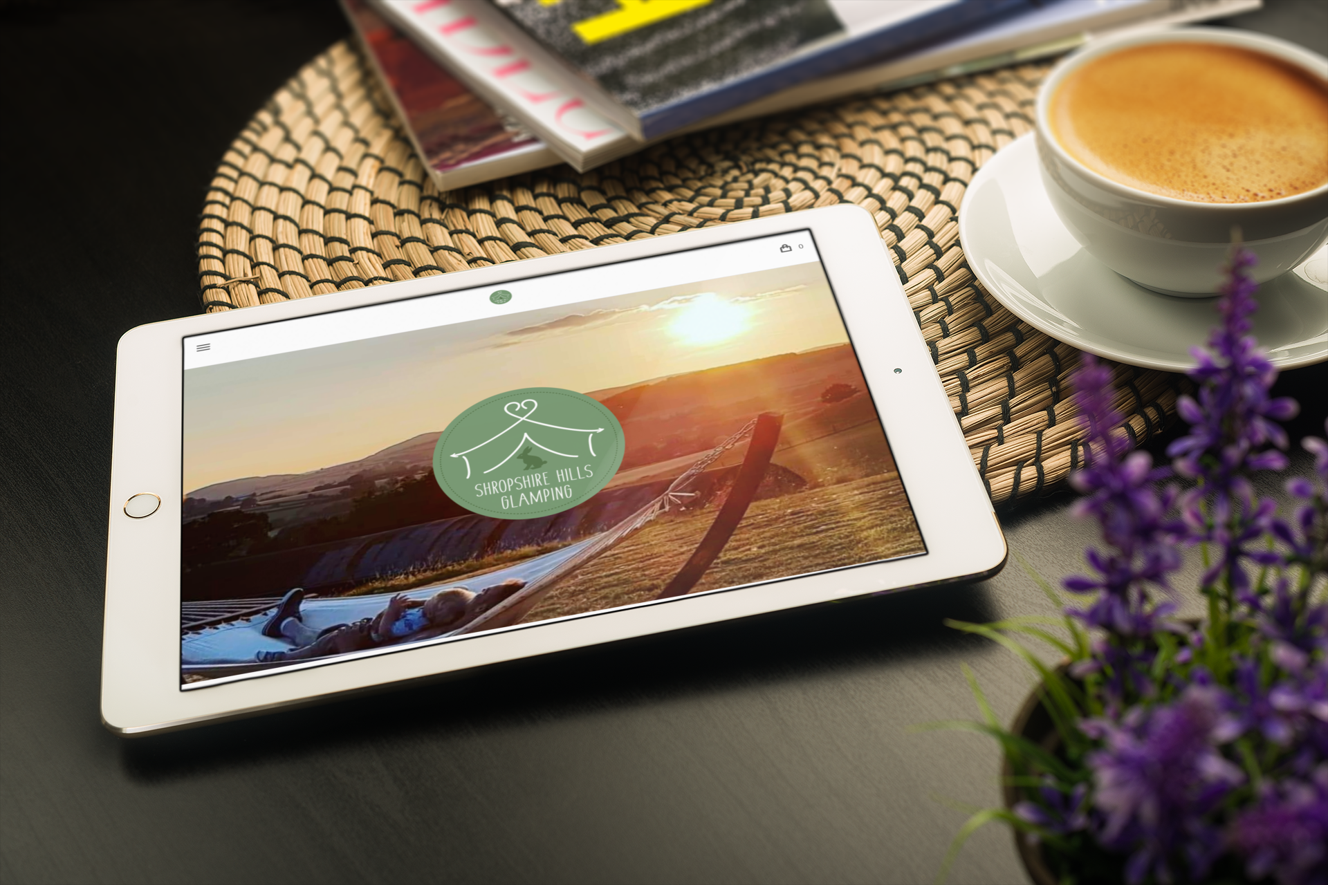 Tablet displaying a nature website, next to coffee cup, magazines, and flowers.