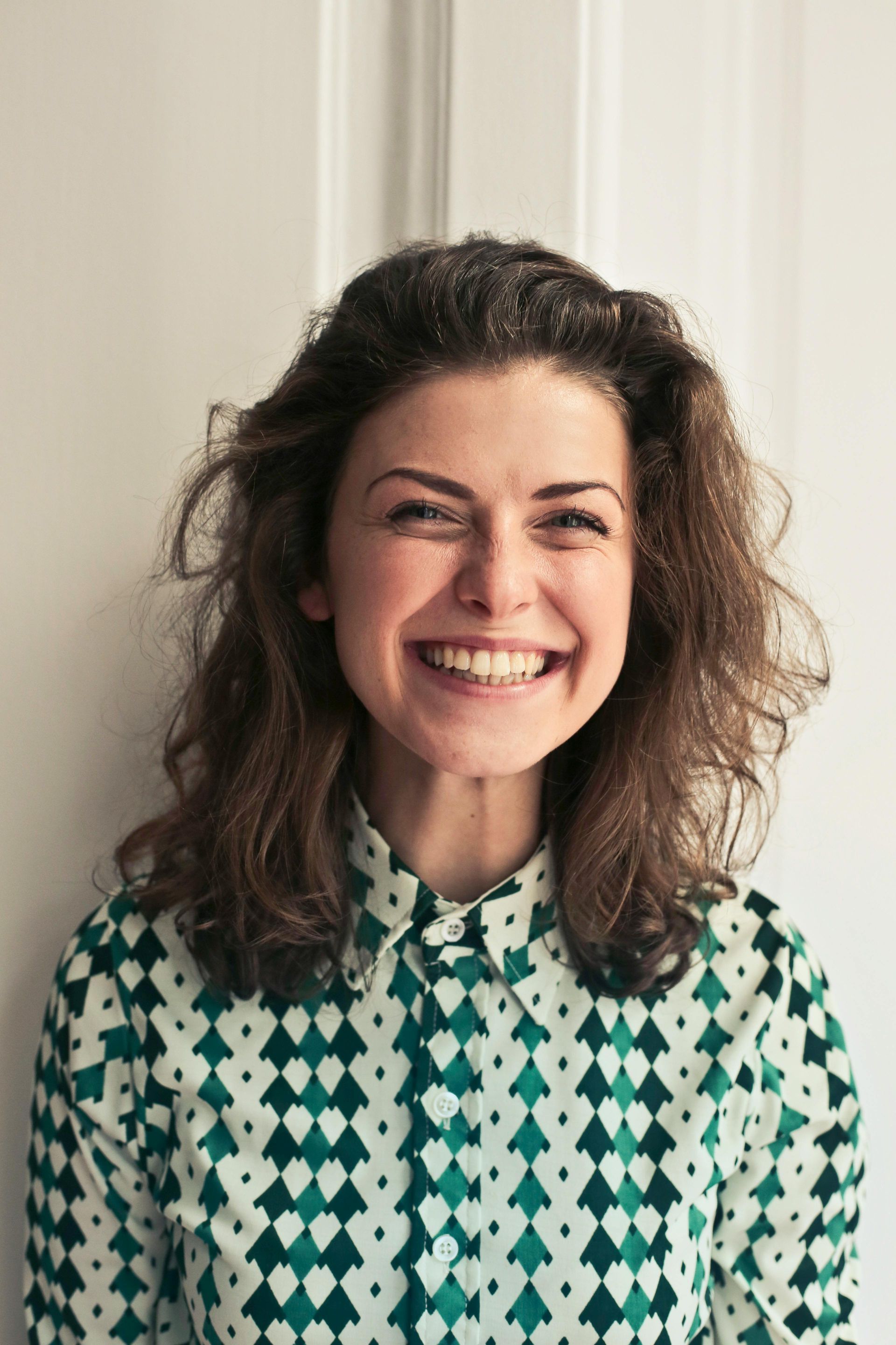 A woman in a green and white shirt is smiling for the camera.