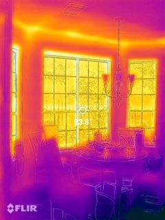 Thermal view of a dining room with large windows, table, and chairs in warm yellow and purple tones