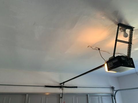 Garage ceiling with a mounted projector and bright light shining on the wall above the door
