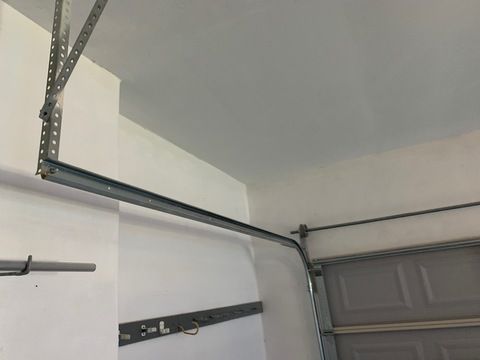 Garage ceiling with metal garage door tracks and opener hardware close-up
