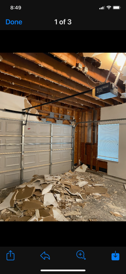 Damaged room with collapsed ceiling, debris on floor, and stacked boxes along the wall