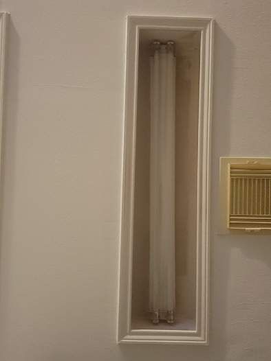 Wall-mounted fluorescent light fixture in a beige hallway