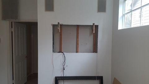 Empty room with a wall cutout, exposed wiring, and a window on the right