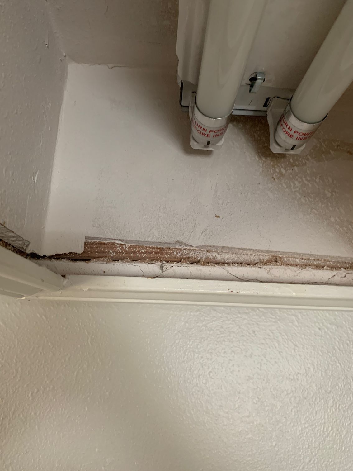 Exposed pipe area above a ceiling, with a crack and peeling paint along the edge