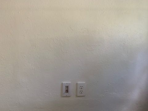 Blank beige wall with two white electrical outlets near the bottom center