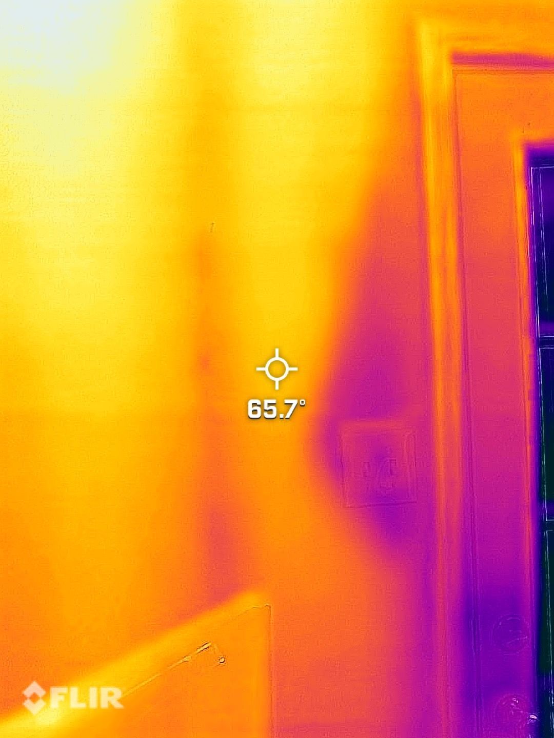 Thermal image of a warm doorway and wall, with a 65.7° spot reading and FLIR overlay