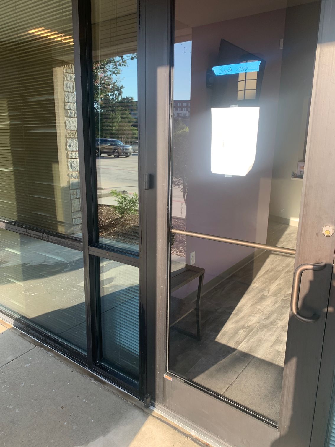 Glass storefront door with a bright notice taped inside and reflections of the street outside