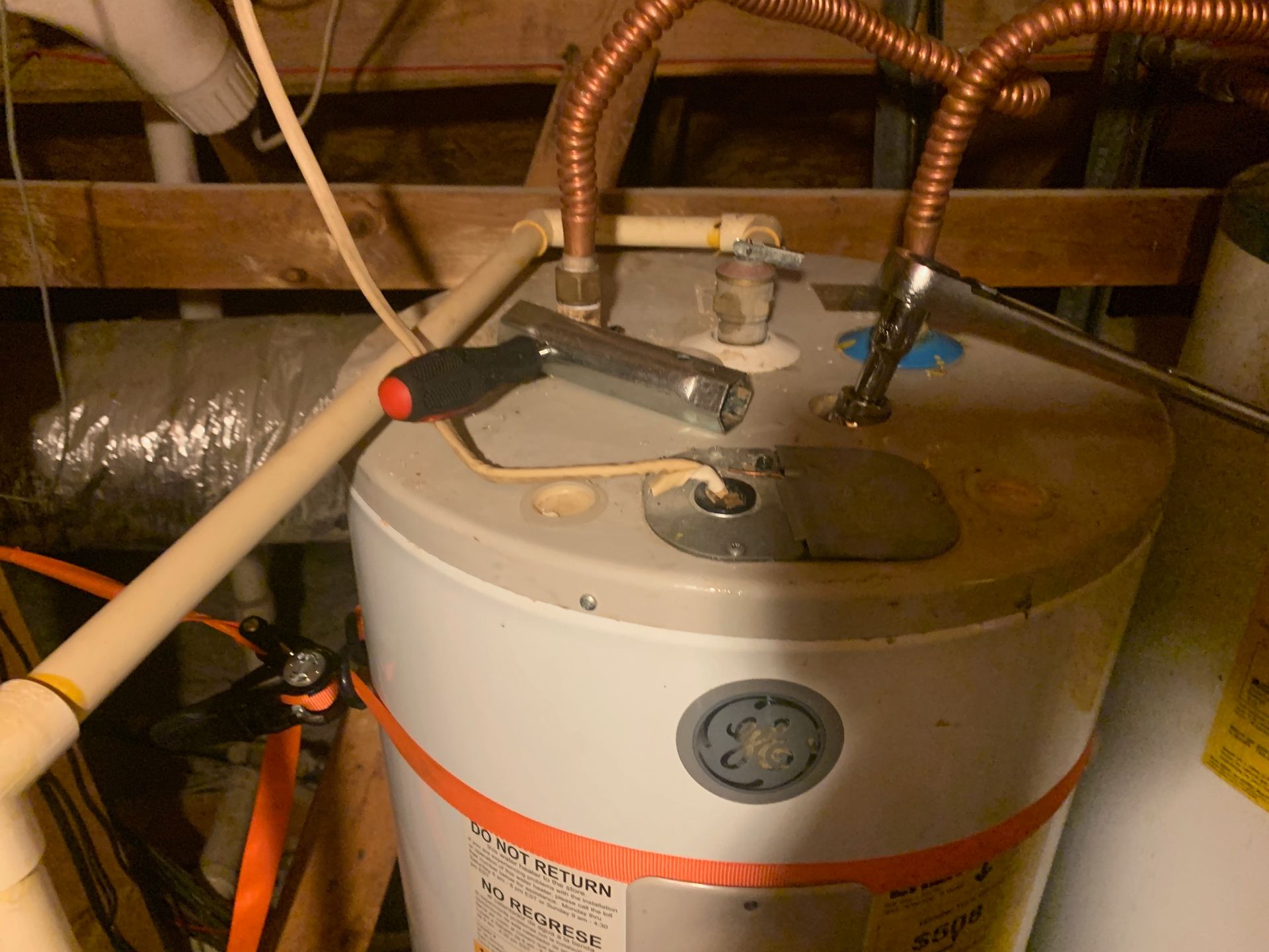 Water heater in a cramped utility space with attached pipes and valves
