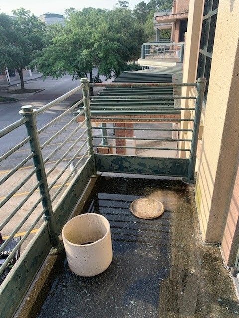 Balcony with metal railing, white bucket, and round tray beside a building