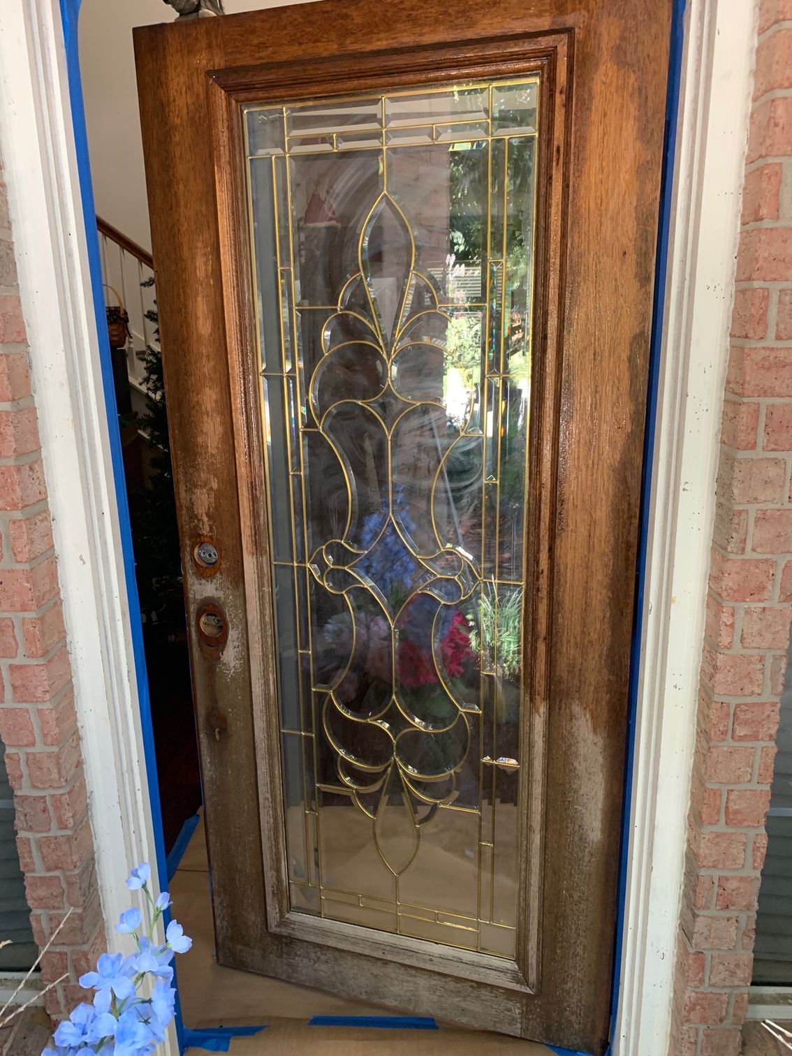 Decorative wooden front door with etched glass panels and metal scrollwork in a brick doorway