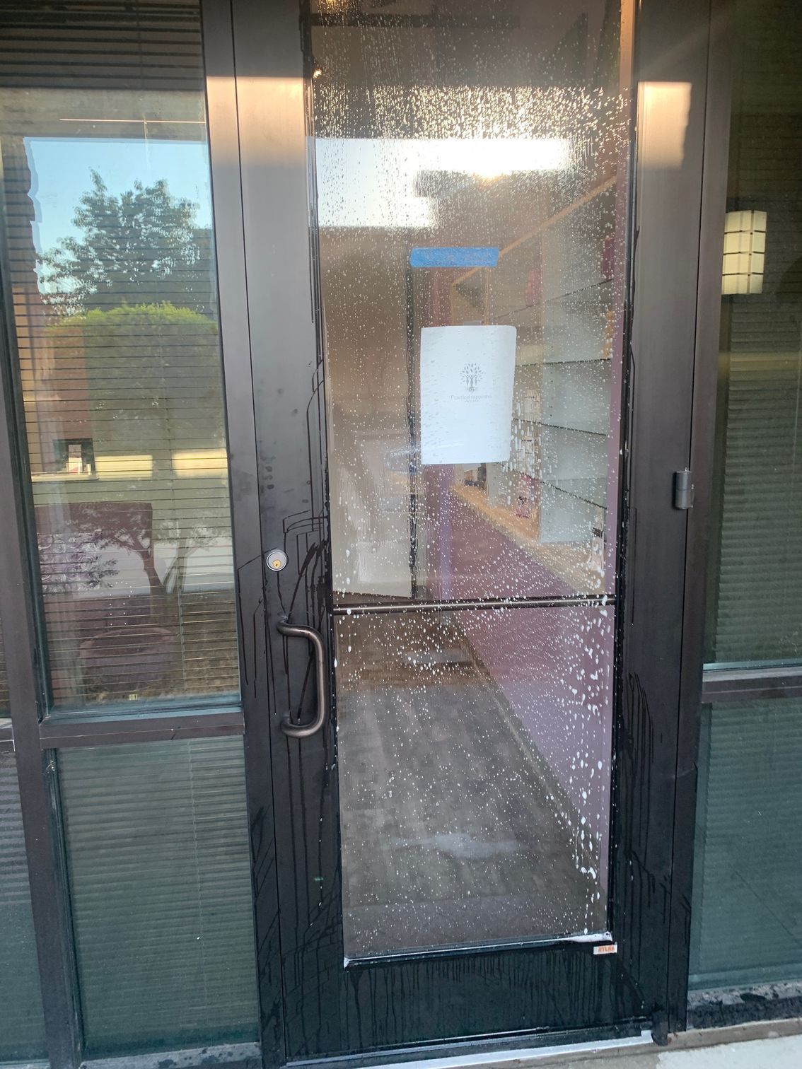 Glass entrance door with shattered panel and a paper notice taped to the center