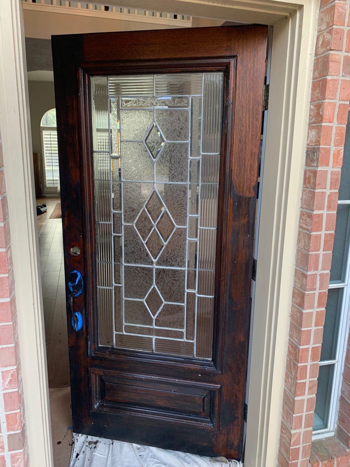 Front door with dark wood finish and decorative glass panel, set in a brick entryway
