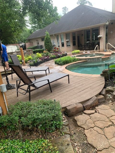 Backyard patio with pool, lounge chairs, stone path, and landscaped garden beside a house