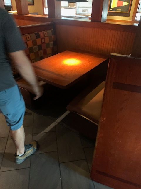 Booth seating in a restaurant with a lit wooden table and a person walking past