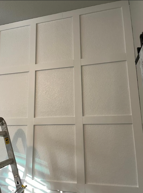 White paneled closet doors in a room, with a ladder partially visible on the left.