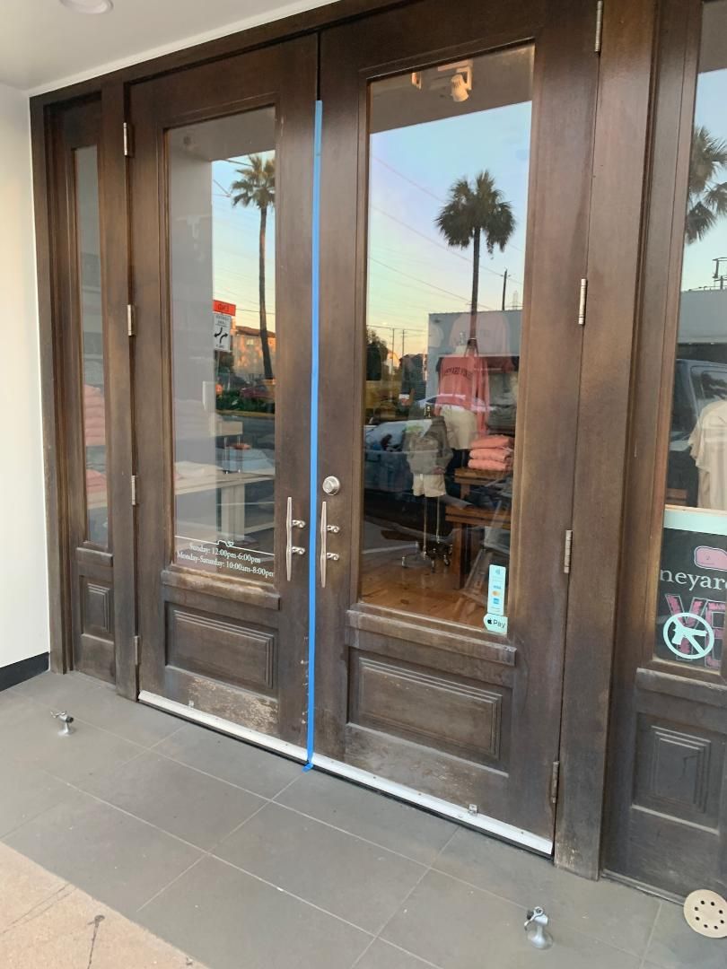 Glass double doors at a storefront entrance with a blue tape strip down the center.