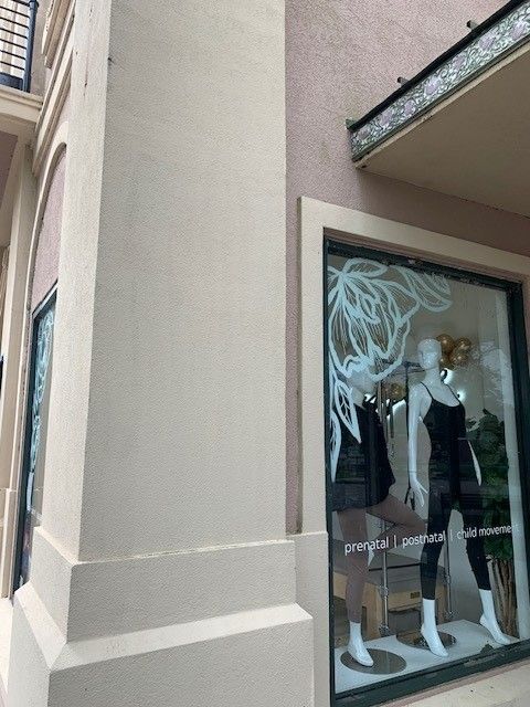 Boutique window display with mannequins in black and white outfits beside a beige building corner