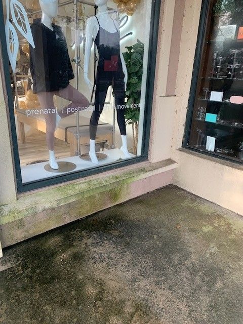 Clothing store window display with mannequins in black and white outfits beside a wet sidewalk