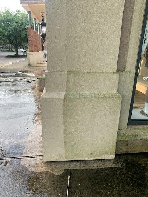 Storefront corner with a beige column and wet sidewalk after rain