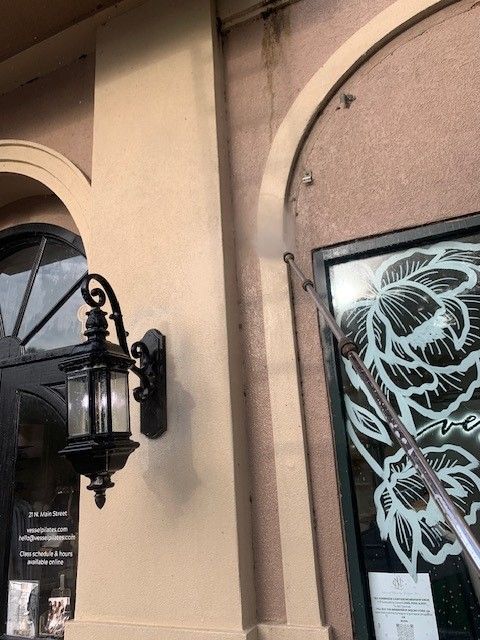 Storefront with black lantern wall light and a leopard graphic poster on a beige stucco wall