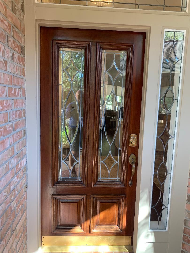 Wooden front door with glass panels and sidelights, framed by a brick entryway.