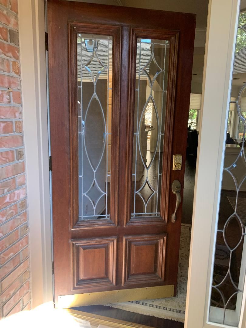 Wooden front door with decorative glass panels beside a brick entryway