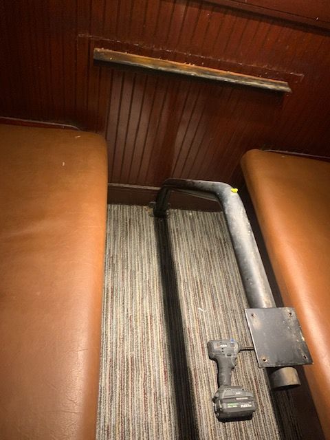 Folded wheelchair beside brown booth seating in a narrow wood-paneled interior.
