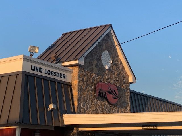Live Lobster restaurant with a crab sign on a stone facade at dusk