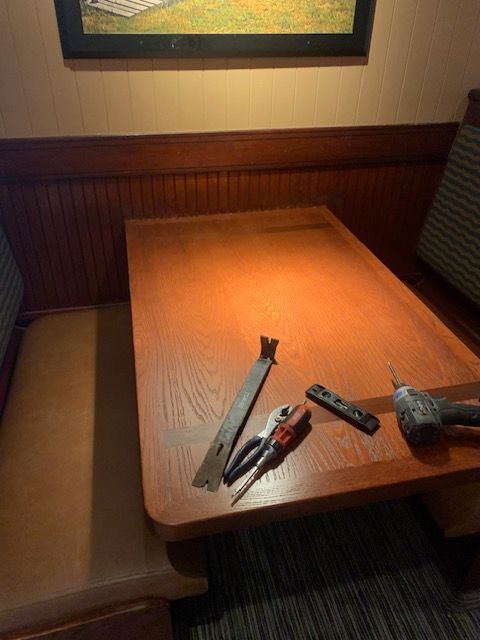 Dining booth table with several knives and a hammer laid out on a wooden surface
